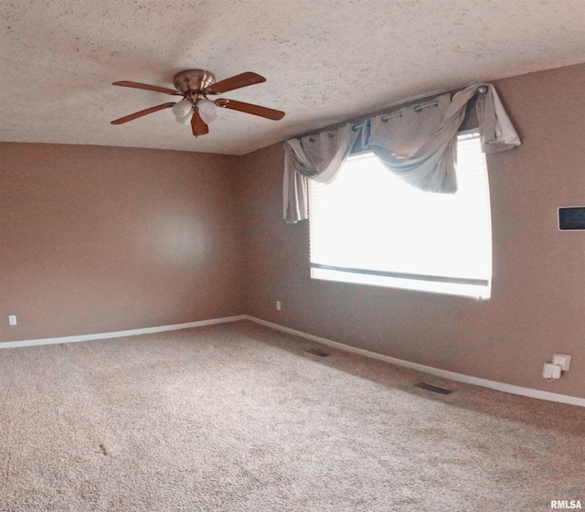 carpeted empty room with a textured ceiling, vaulted ceiling, and ceiling fan