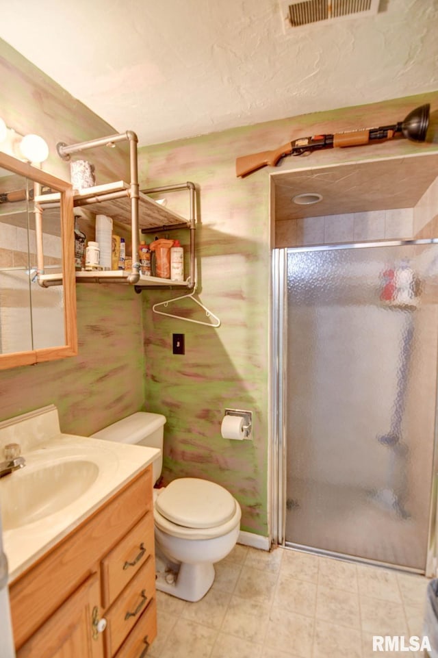 bathroom featuring tile patterned floors, toilet, a shower with door, and vanity