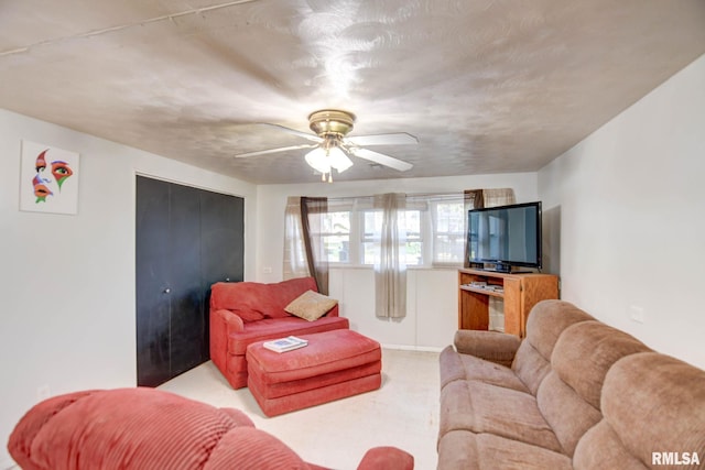 living room featuring ceiling fan, light colored carpet, and a textured ceiling