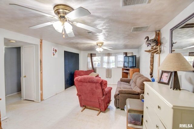 living room with ceiling fan and a textured ceiling