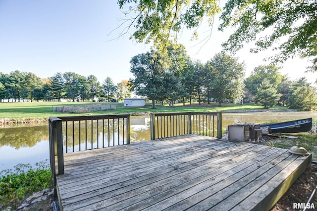 wooden terrace featuring a water view, a storage unit, and a yard