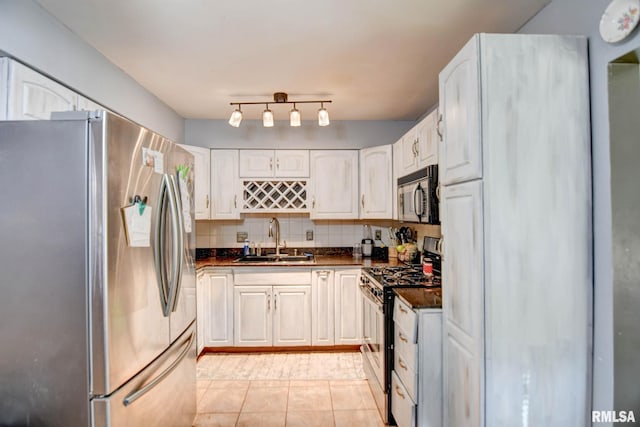 kitchen featuring sink, white cabinetry, appliances with stainless steel finishes, light tile patterned floors, and backsplash