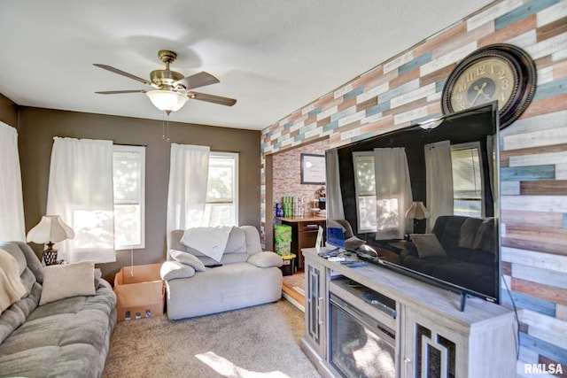 carpeted living room featuring ceiling fan and wood walls