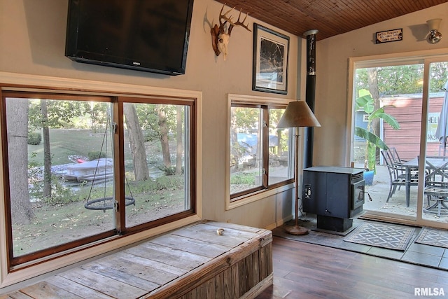 sunroom featuring a wood stove, a healthy amount of sunlight, and wooden ceiling