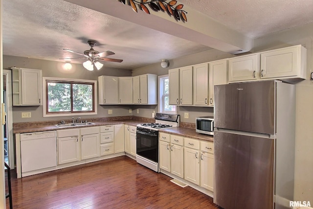 kitchen with ceiling fan, dark wood-type flooring, sink, stainless steel appliances, and a textured ceiling