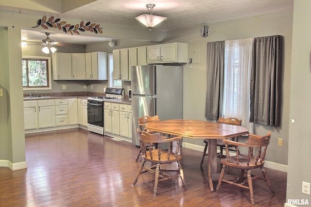 kitchen with ceiling fan, sink, white gas range oven, stainless steel refrigerator, and dark hardwood / wood-style floors