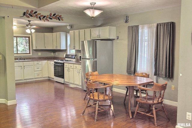kitchen featuring range with gas stovetop, baseboards, dark wood-style flooring, freestanding refrigerator, and a sink