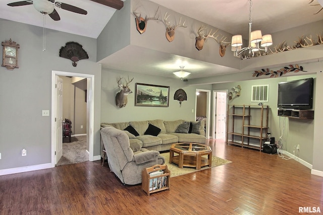 living room with dark wood-type flooring, ceiling fan with notable chandelier, and a towering ceiling