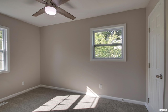 spare room with ceiling fan, a wealth of natural light, and carpet