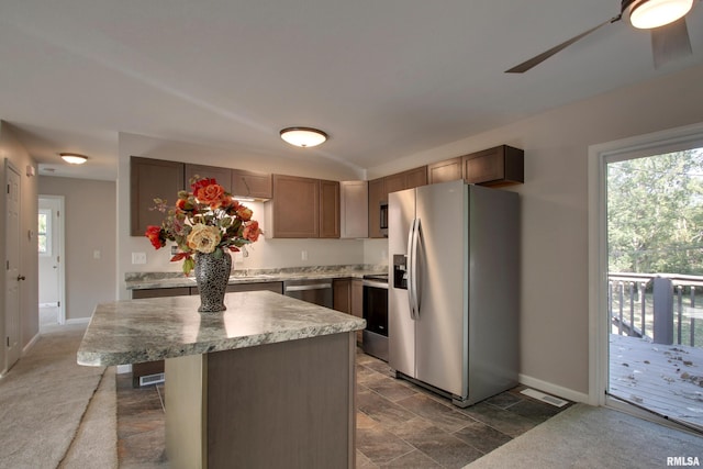 kitchen with ceiling fan, stainless steel appliances, dark colored carpet, and a center island