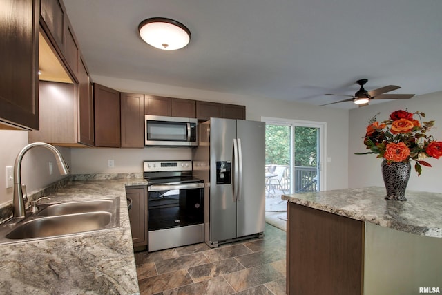 kitchen with dark brown cabinetry, light stone counters, ceiling fan, sink, and appliances with stainless steel finishes