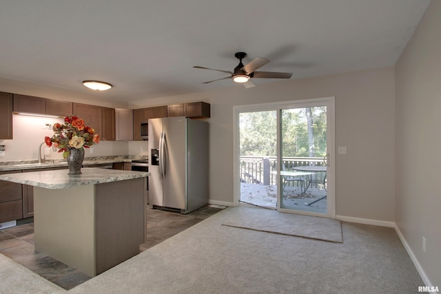 kitchen with ceiling fan, light colored carpet, a kitchen island, sink, and stainless steel appliances