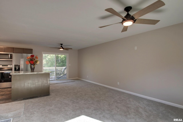 kitchen with light stone counters, stainless steel appliances, carpet, and a kitchen island