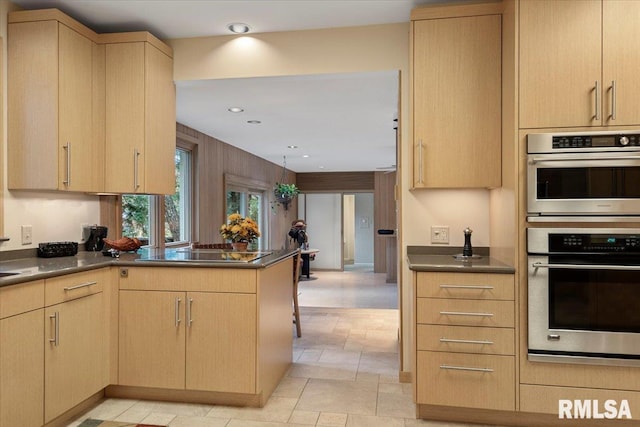 kitchen with light brown cabinetry, stainless steel double oven, black electric stovetop, and kitchen peninsula