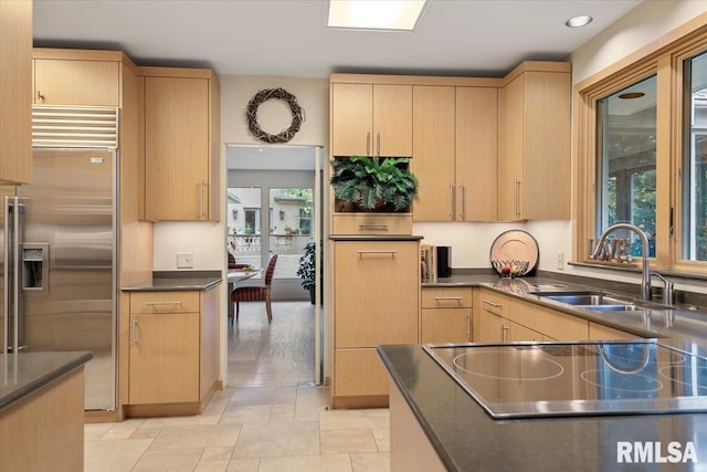 kitchen with built in fridge, sink, and light brown cabinetry