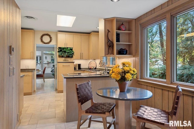 kitchen featuring sink, light brown cabinets, kitchen peninsula, and wooden walls