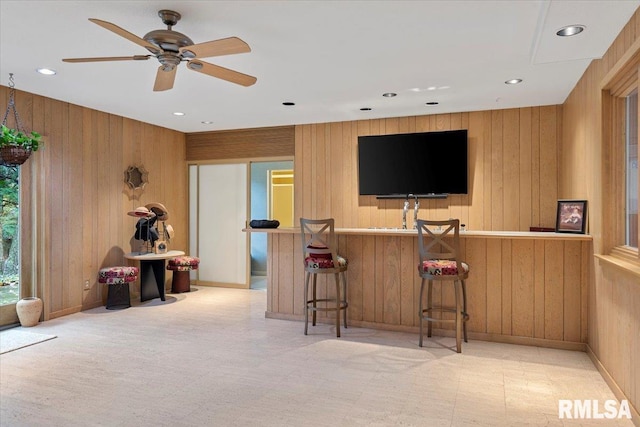 bar with ceiling fan and wooden walls