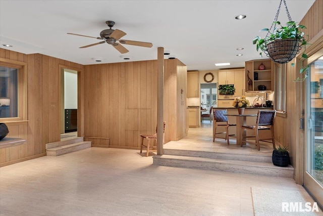 living room featuring ceiling fan, sink, and wooden walls