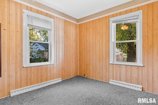 spare room featuring carpet, a baseboard heating unit, and wooden walls