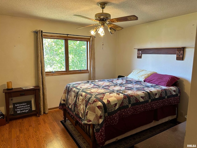 bedroom with ceiling fan, a textured ceiling, and light hardwood / wood-style flooring