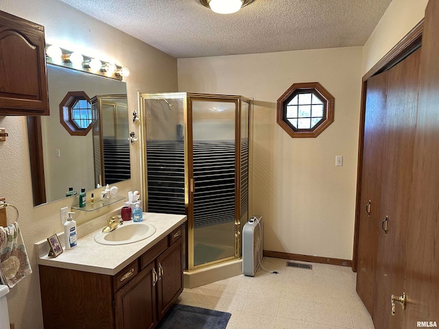 bathroom featuring vanity, a textured ceiling, and a shower with door