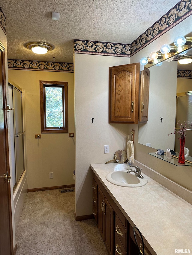 full bathroom with vanity, toilet, a textured ceiling, and bath / shower combo with glass door