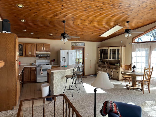 kitchen featuring white appliances, lofted ceiling with skylight, light carpet, and wood ceiling