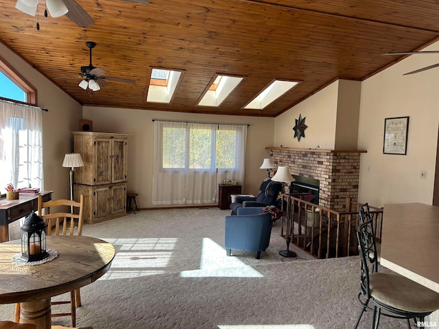 living room with light carpet, vaulted ceiling with skylight, wooden ceiling, and ceiling fan