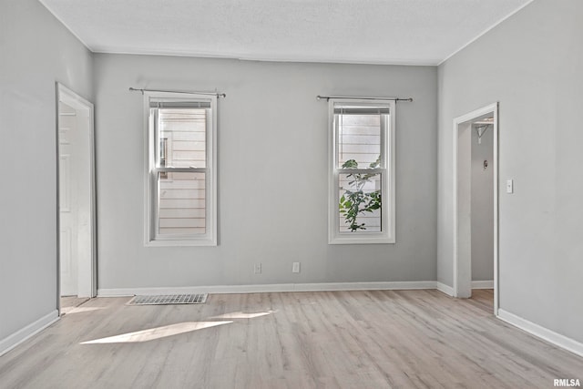 empty room with a textured ceiling and light wood-type flooring