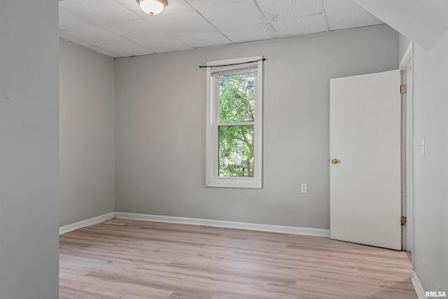 spare room featuring light hardwood / wood-style floors and a paneled ceiling