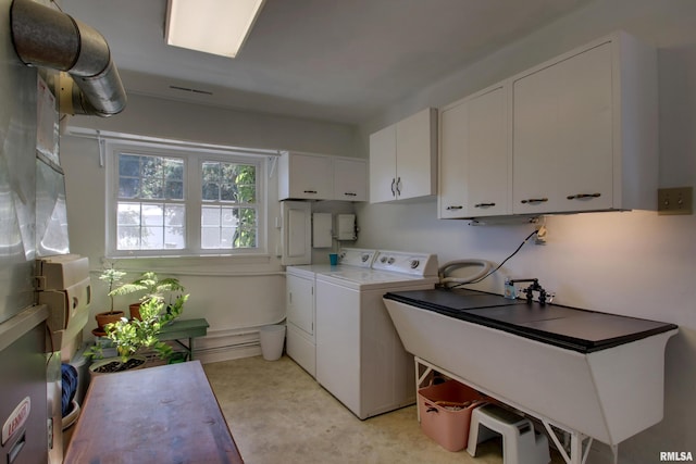 laundry area with sink, a baseboard heating unit, washing machine and clothes dryer, and cabinets