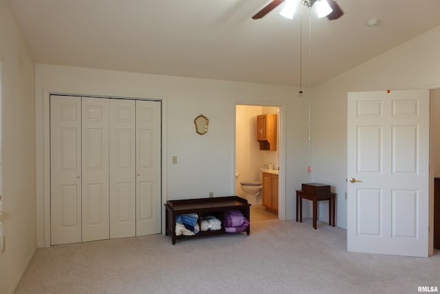 bedroom with ceiling fan, a closet, light carpet, and vaulted ceiling