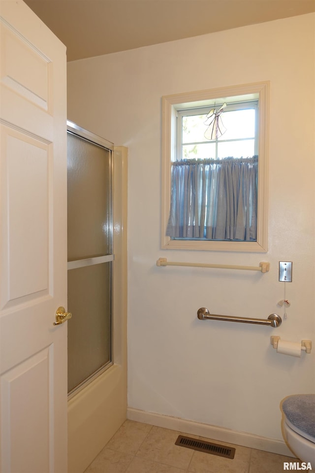 bathroom with tile patterned floors, enclosed tub / shower combo, and toilet