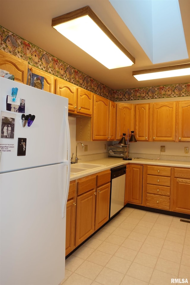 kitchen featuring dishwasher, white refrigerator, and sink