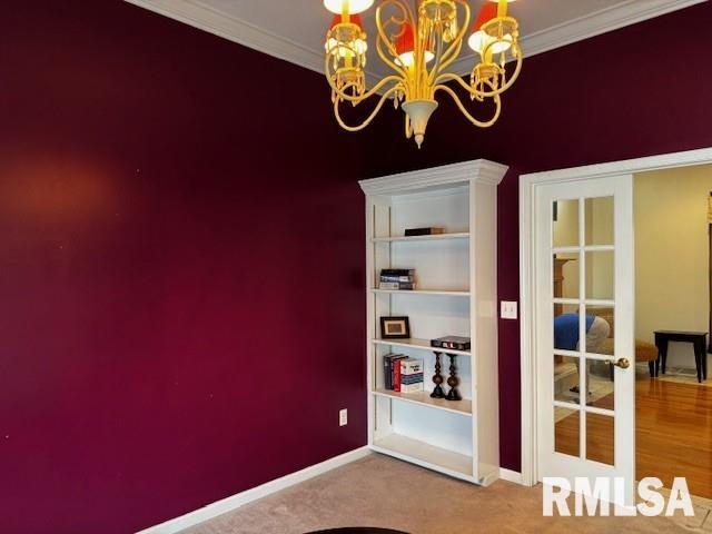 empty room featuring carpet, ornamental molding, french doors, and a notable chandelier