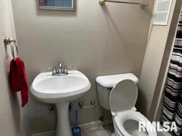 bathroom with tile patterned floors, curtained shower, and toilet