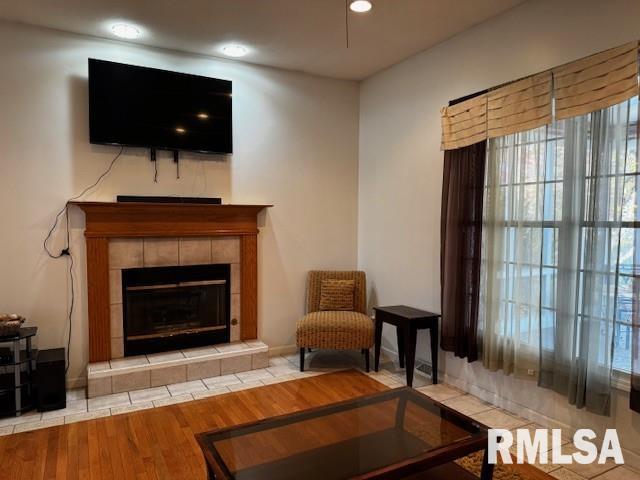 living area with a tile fireplace and light hardwood / wood-style floors