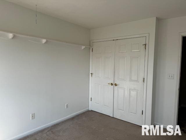 unfurnished bedroom featuring dark colored carpet and a closet