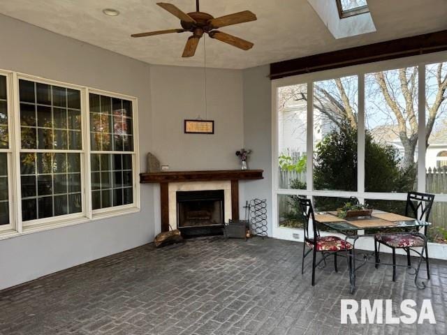 sunroom featuring a skylight, ceiling fan, and a fireplace