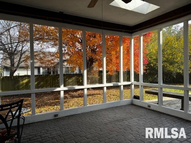 unfurnished sunroom with a skylight, ceiling fan, and a healthy amount of sunlight