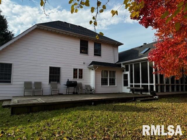 back of property with a sunroom and a lawn