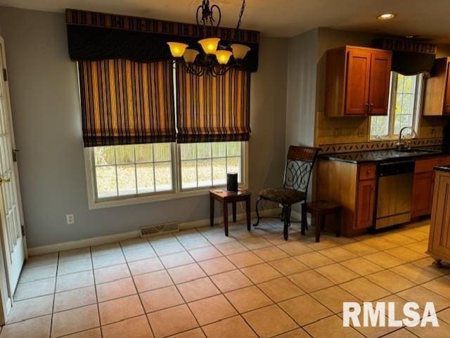 kitchen with a chandelier, a wealth of natural light, light tile patterned floors, and stainless steel dishwasher