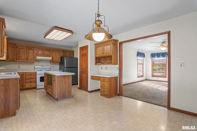 kitchen with fridge, gas range gas stove, sink, decorative light fixtures, and a center island