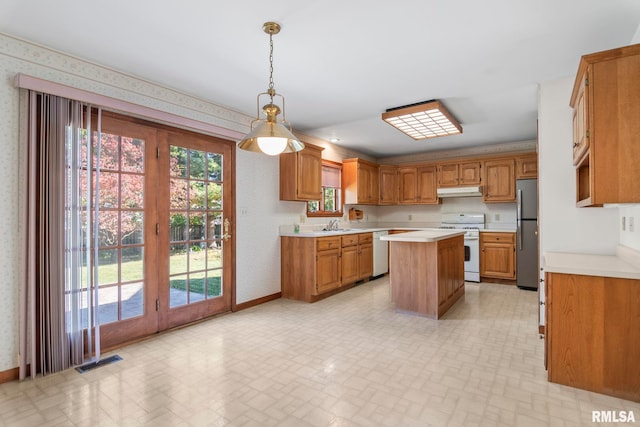 kitchen with white appliances, sink, a center island, and decorative light fixtures