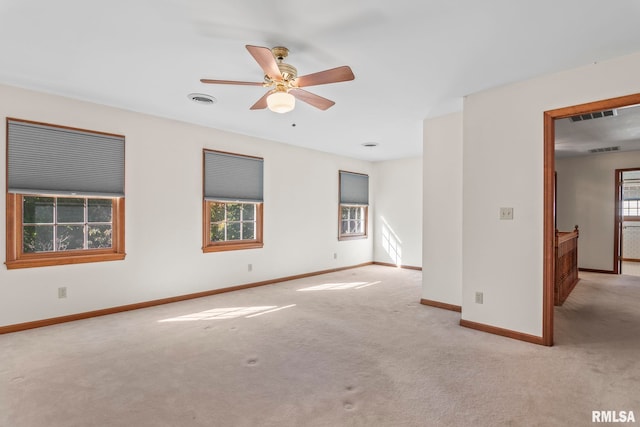 empty room with ceiling fan, light colored carpet, and plenty of natural light