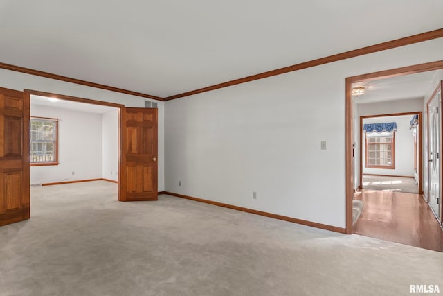 carpeted spare room featuring ornamental molding and a healthy amount of sunlight