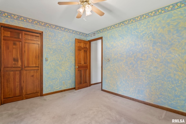 unfurnished bedroom with a closet, light colored carpet, and ceiling fan