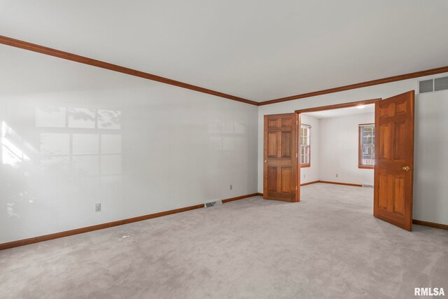 empty room featuring ornamental molding and light colored carpet