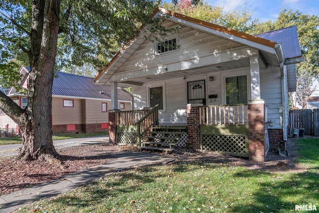 view of front of property with covered porch, a front yard, and central AC unit