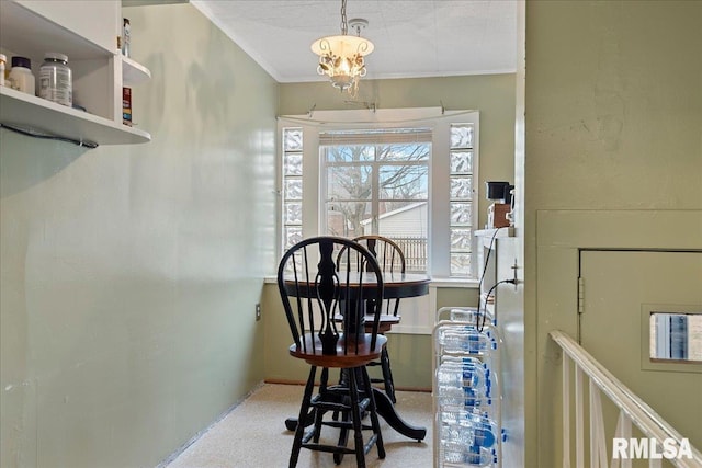 dining area with ornamental molding, an inviting chandelier, and light colored carpet